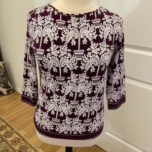 Deep purple background accents, the rows of trees in decorative pots